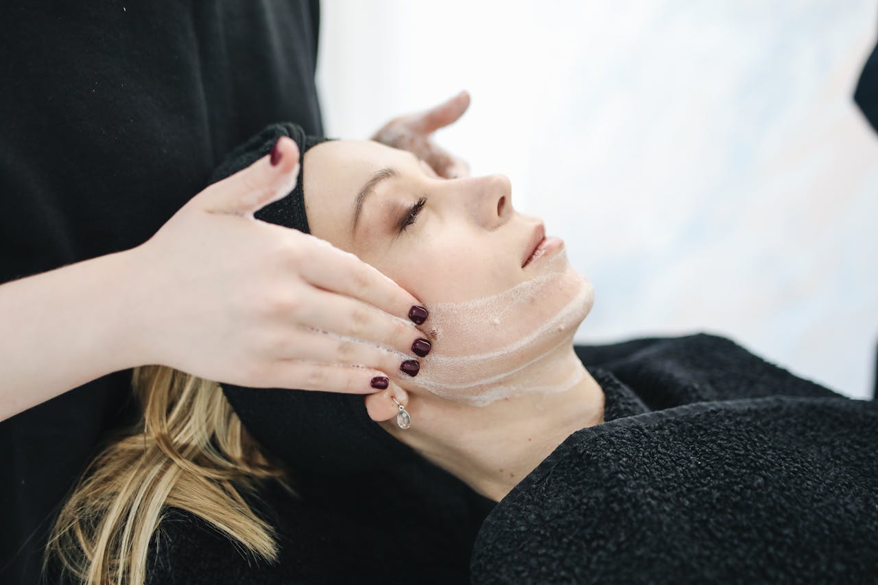 Home Side view of a woman receiving a soothing facial treatment at a spa, promoting wellness and skincare.